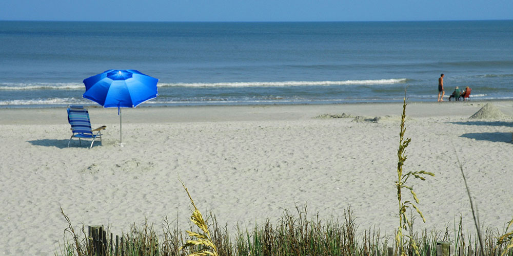 A blue umbrella and chair on the beach